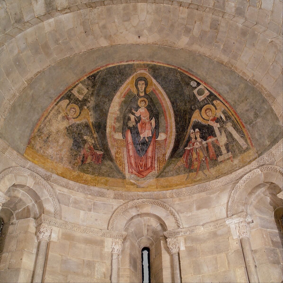 The enthroned Virgin and Child inside an almond-shaped painted frame, flanked by angels and the Magi, displayed in a stone apse at The Met Cloisters.